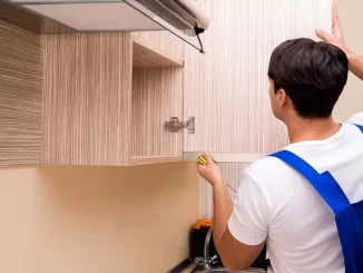 a man in a blue overalls measuring a shelf